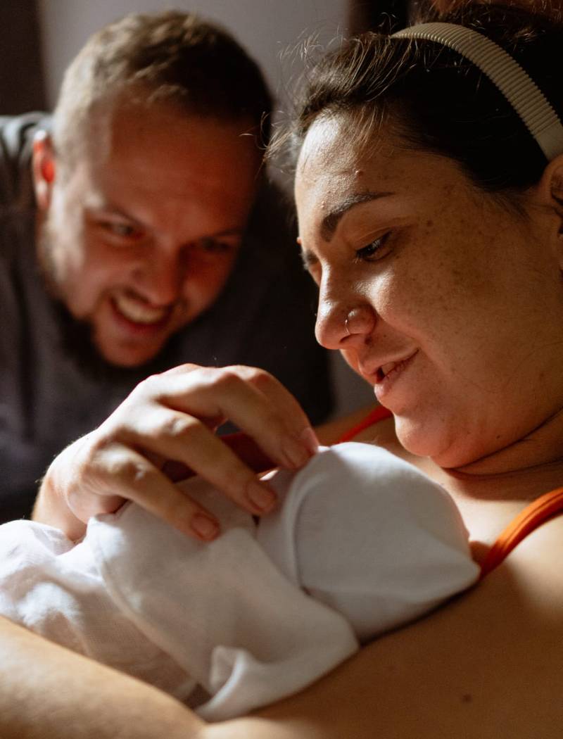 Mãe e pai olham com carinho para o bebê recém-nascido logo após o nascimento