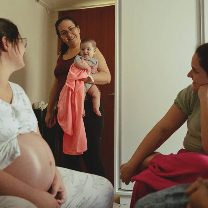 Arielle Matos segura um bebê no colo e sorri durante conversa com gestantes